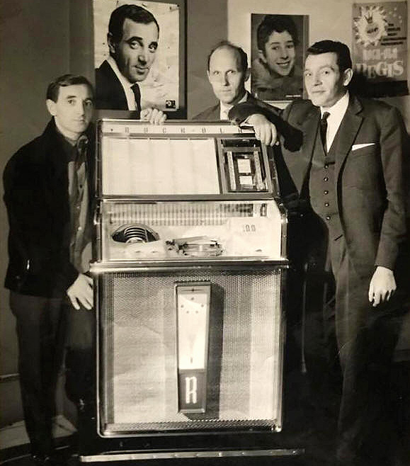 Voorstelling van een nieuwe Rockola jukebox met M. Desimpelare (midden) en links - JAWEL! - de Franse zanger Charles Aznavour!